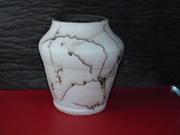 a white and brown vase on a red surface