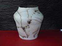 a white and brown vase on a red surface