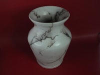 a white and black vase on a red background